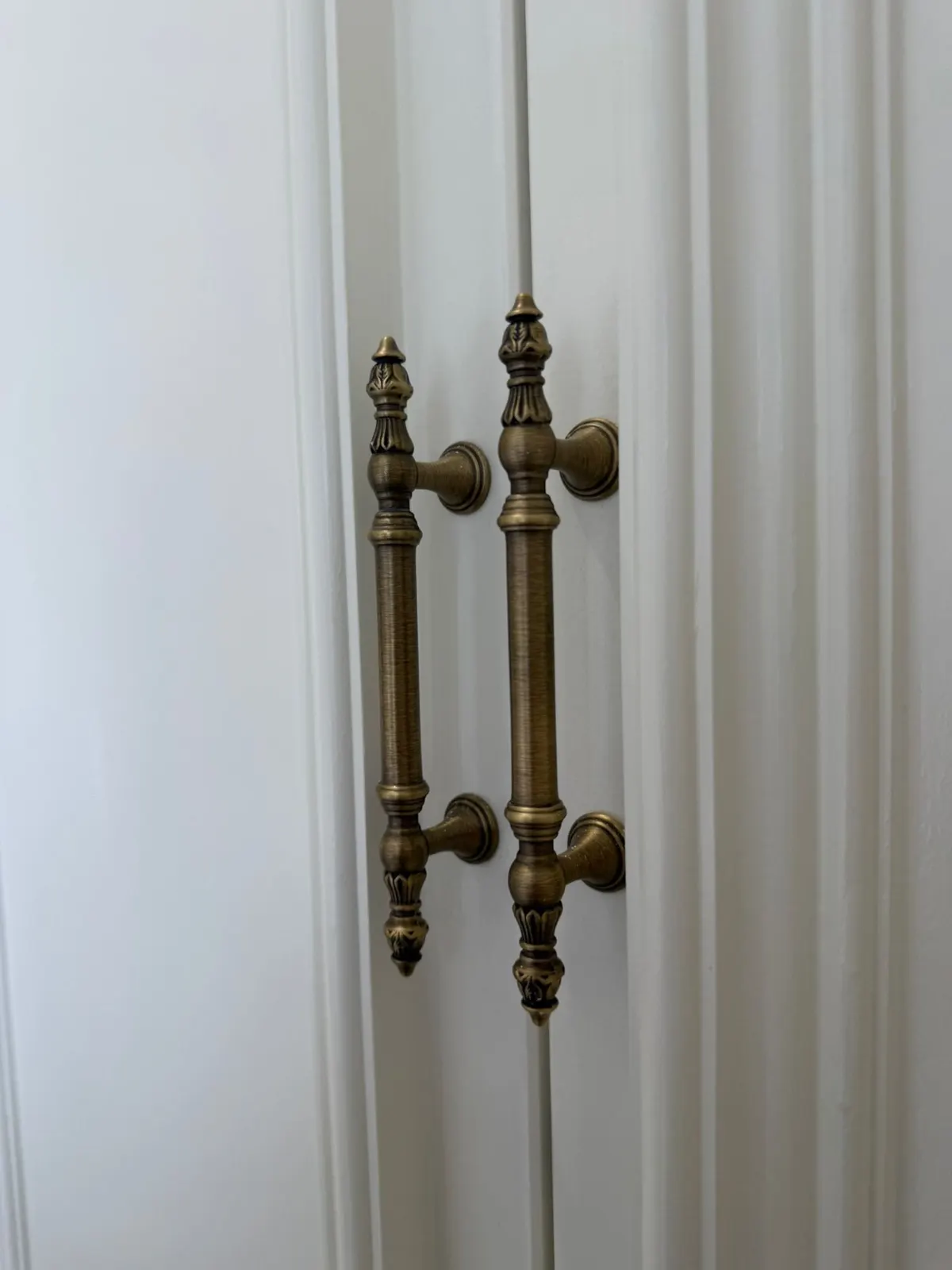Ornate antique brass handles on freshly finished white joinery