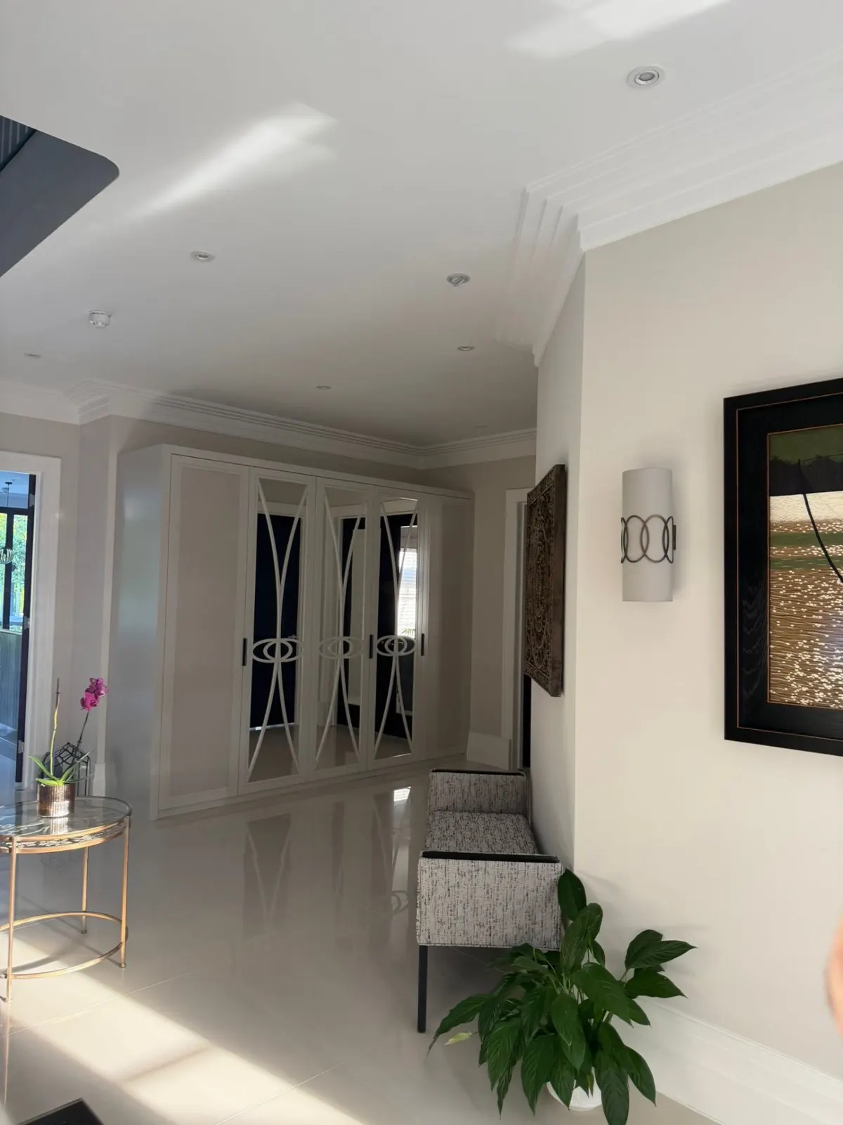 Finished hallway with mirrored wardrobes and an orchid