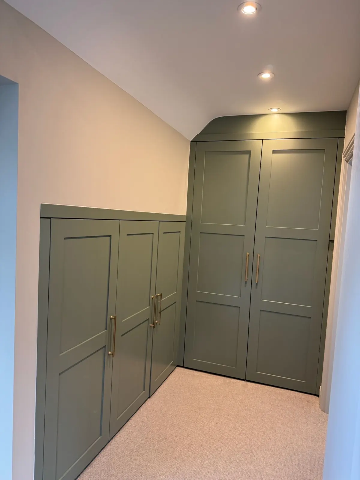 Sage green fitted wardrobes in a loft room