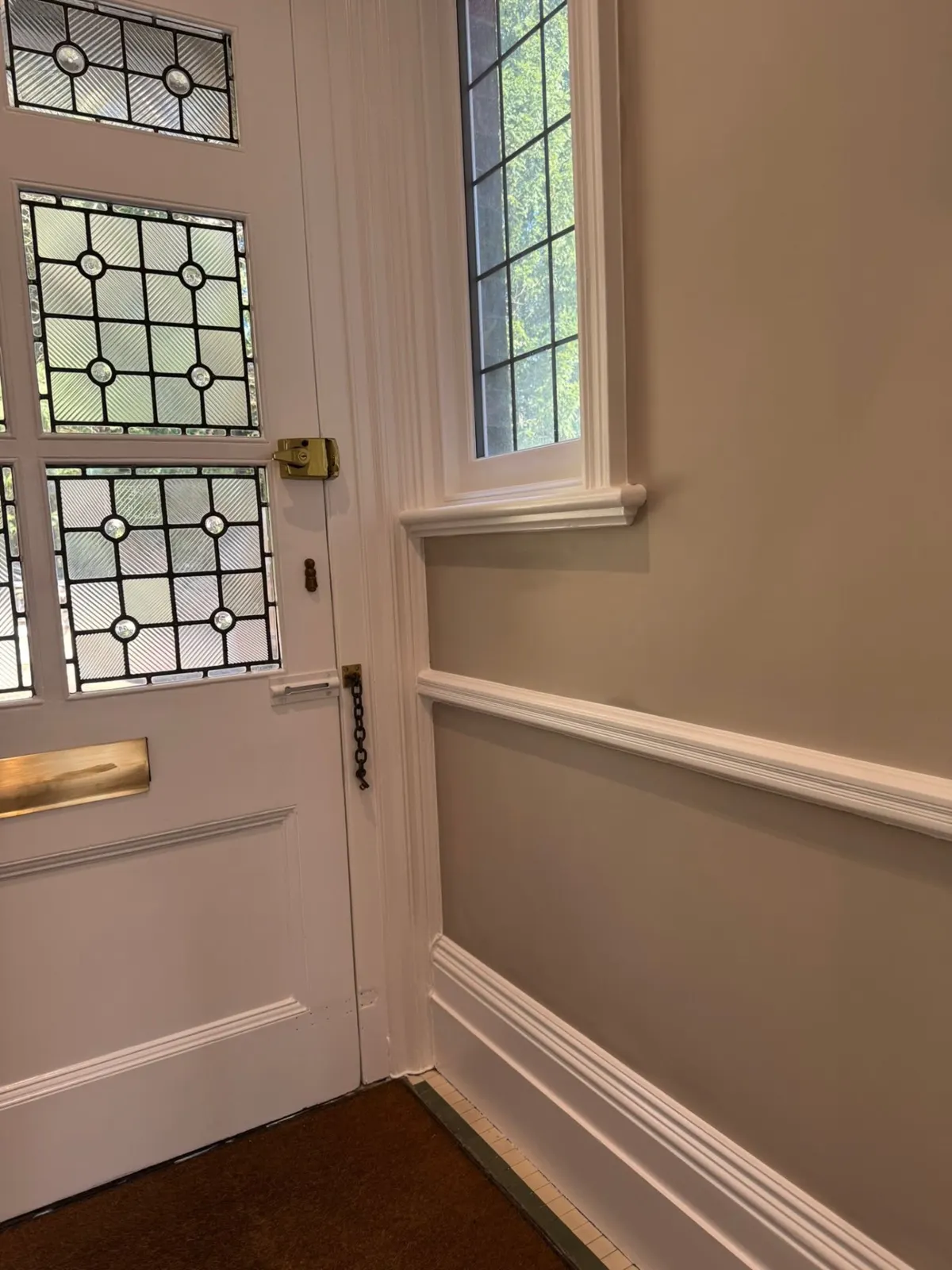 Leaded-glass door beside white wall panelling